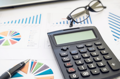 Flat lay image of calculator, glasses, and graphs