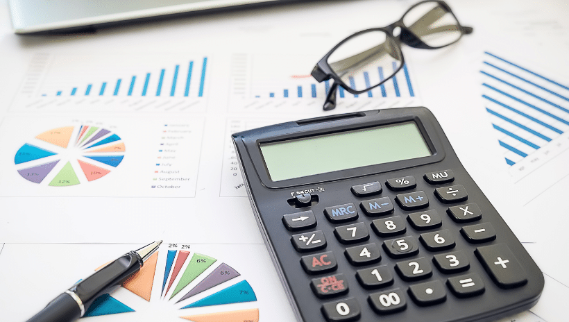 Flat lay image of calculator, glasses, and graphs